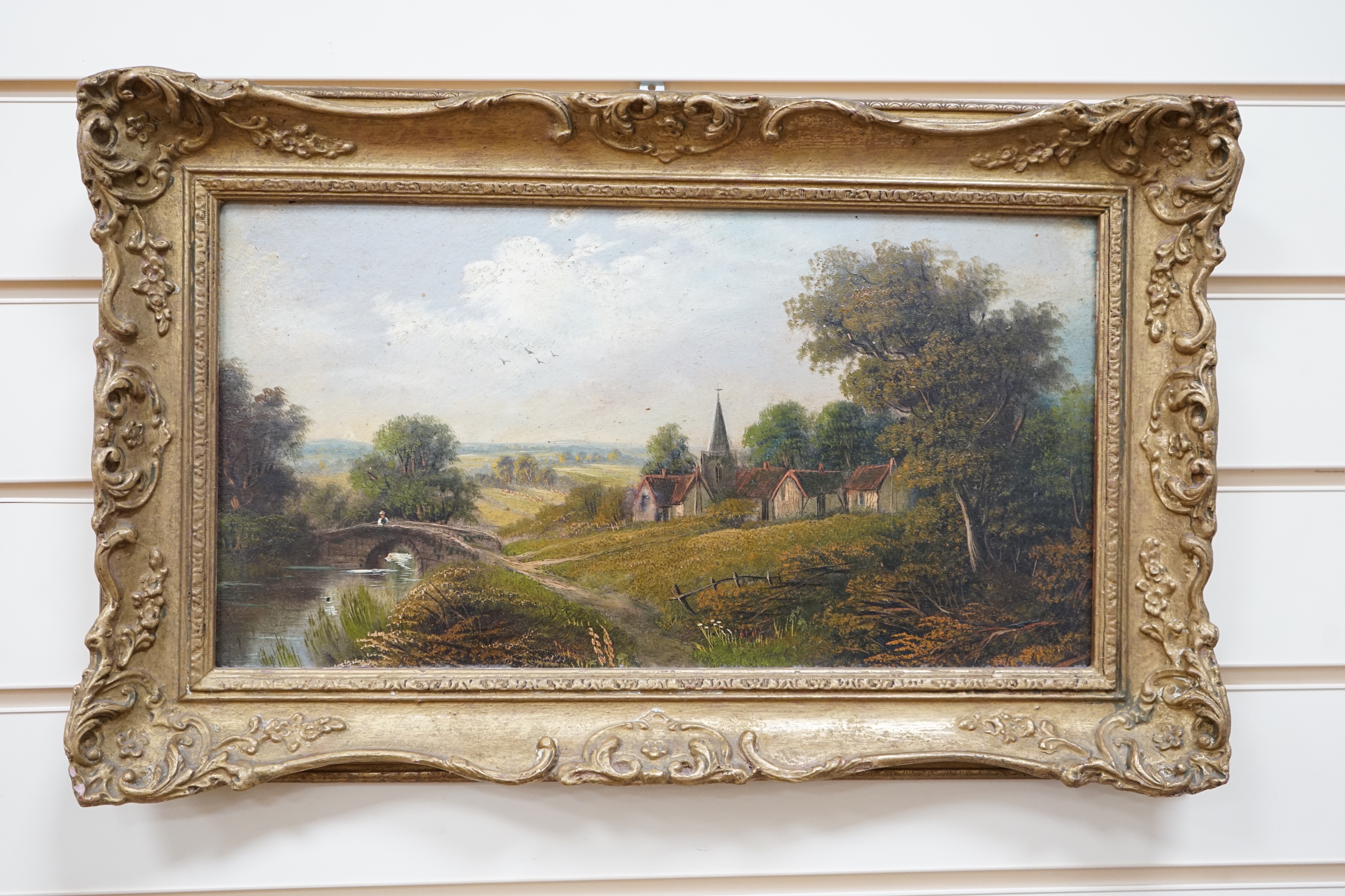 English School c.1900, oil on canvas, River beyond village scene, unsigned, 23 x 43cm